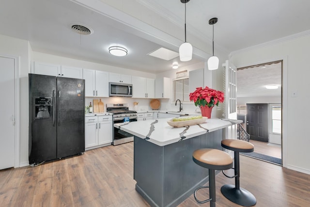 kitchen featuring white cabinets, sink, hanging light fixtures, light hardwood / wood-style flooring, and stainless steel appliances