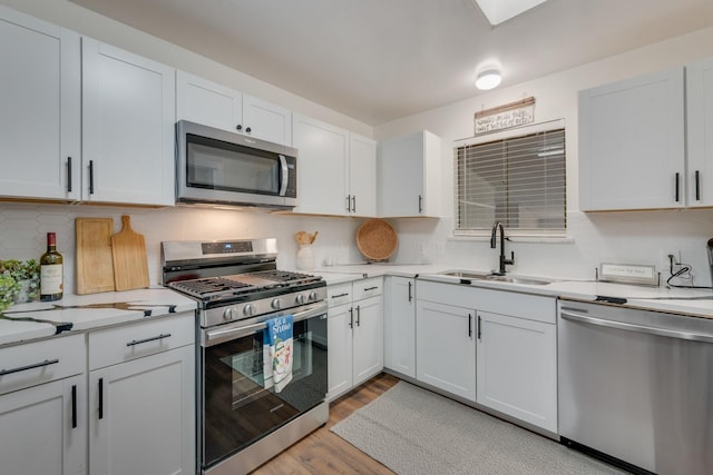 kitchen featuring white cabinets, stainless steel appliances, light hardwood / wood-style floors, and sink