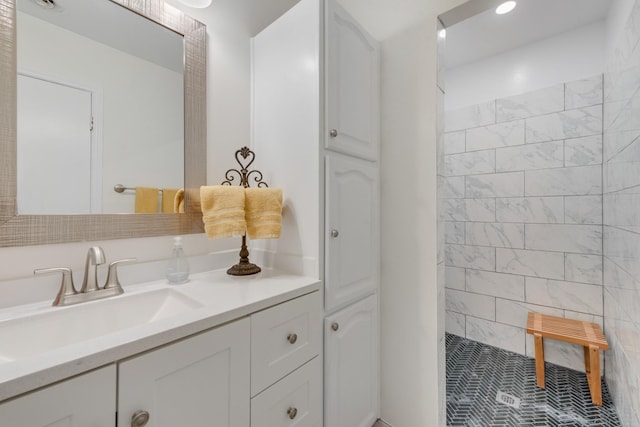 bathroom featuring tiled shower and vanity