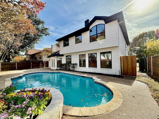 rear view of property with a fenced in pool