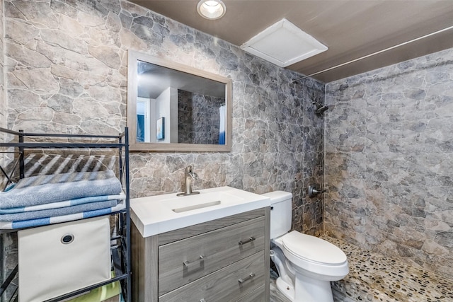 bathroom with tiled shower, vanity, and toilet