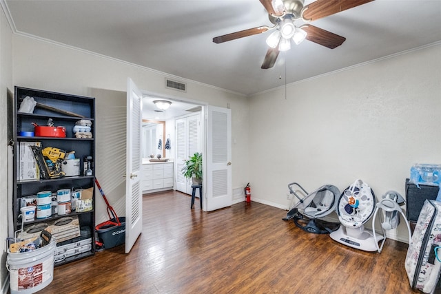 misc room with ceiling fan, dark wood-type flooring, and ornamental molding