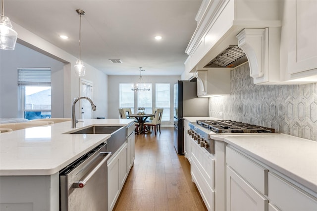 kitchen featuring sink, white cabinetry, hanging light fixtures, a center island with sink, and stainless steel appliances