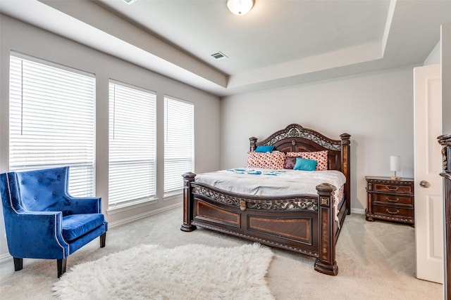 bedroom with a tray ceiling and light colored carpet