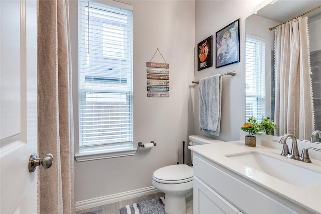 bathroom featuring plenty of natural light, vanity, hardwood / wood-style floors, and toilet