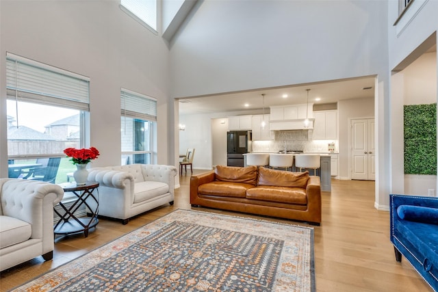 living room featuring a towering ceiling and light wood-type flooring