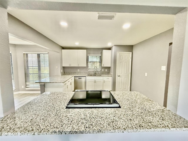 kitchen featuring black electric stovetop, kitchen peninsula, sink, white cabinetry, and stainless steel dishwasher