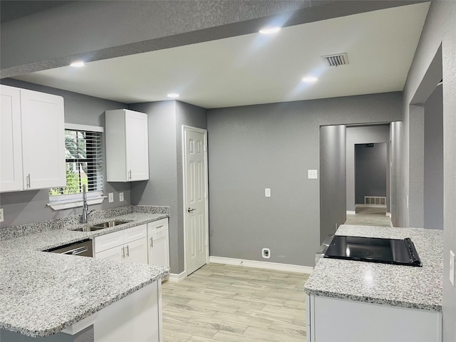 kitchen with white cabinets, kitchen peninsula, light stone countertops, and sink