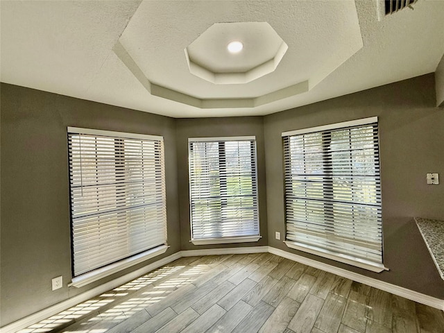 unfurnished room with a textured ceiling and a raised ceiling