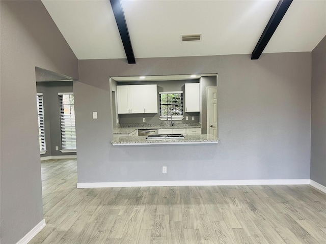 interior space with kitchen peninsula, light stone countertops, light hardwood / wood-style flooring, white cabinets, and vaulted ceiling with beams