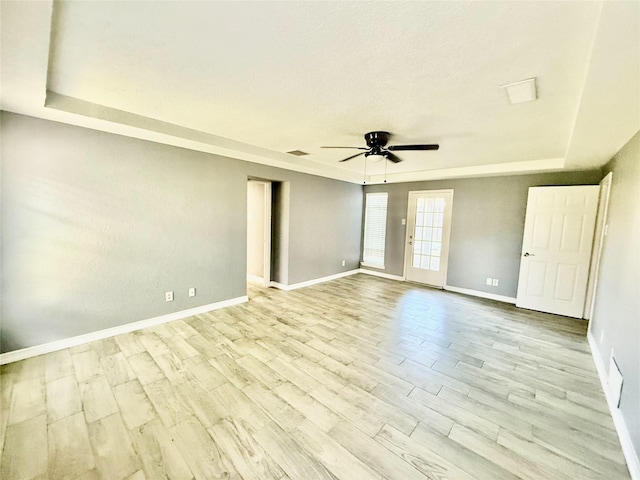 spare room featuring ceiling fan, a tray ceiling, and light hardwood / wood-style flooring