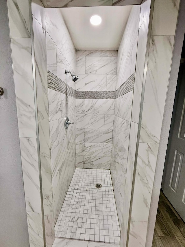 bathroom featuring tiled shower and wood-type flooring