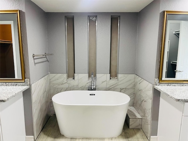 bathroom with tile walls, a tub, and vanity