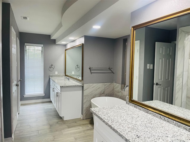 bathroom with vanity, tile walls, hardwood / wood-style floors, and a tub