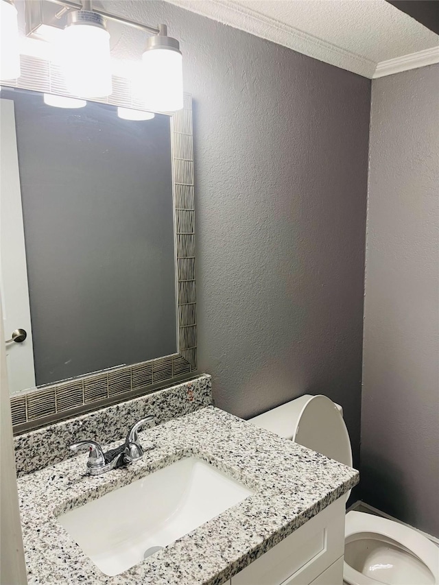 bathroom with ornamental molding, vanity, and toilet