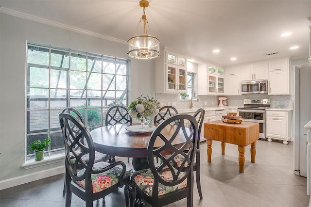 tiled dining area featuring crown molding, a healthy amount of sunlight, and a notable chandelier