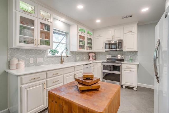 512 N Parkridge Dr, Mansfield, TX 76063 - kitchen featuring appliances with stainless steel finishes, white cabinets, backsplash, crown molding, and light tile patterned floors