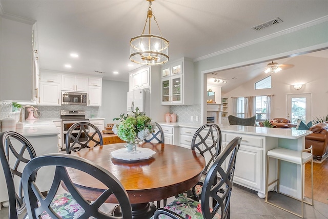 dining space with sink, crown molding, vaulted ceiling, and ceiling fan with notable chandelier