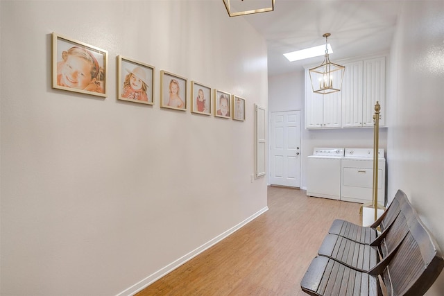hallway featuring an inviting chandelier, baseboards, light wood-type flooring, separate washer and dryer, and a skylight