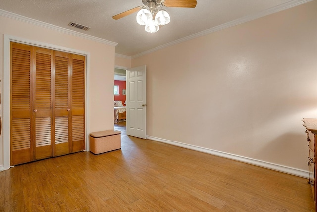 unfurnished bedroom featuring crown molding, ceiling fan, light hardwood / wood-style floors, and a closet