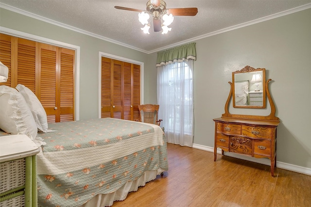 bedroom featuring crown molding, a textured ceiling, light wood-type flooring, multiple closets, and ceiling fan