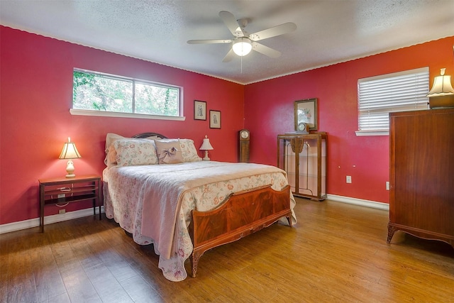 bedroom featuring multiple windows, hardwood / wood-style flooring, and a textured ceiling