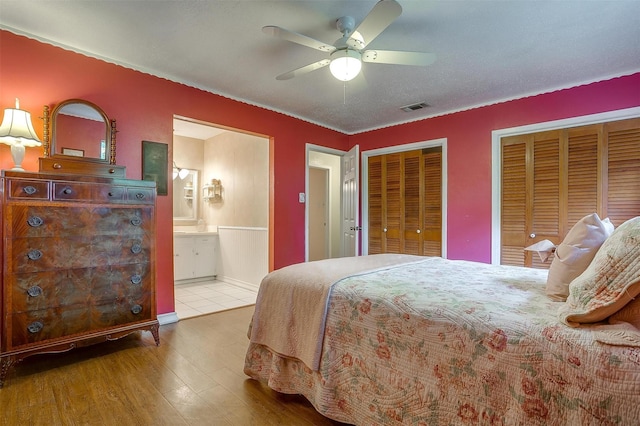 bedroom featuring multiple closets, ceiling fan, wood-type flooring, and ensuite bathroom