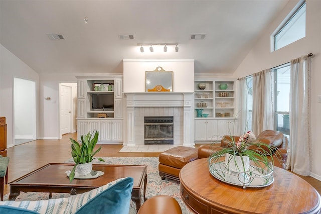 512 N Parkridge Dr, Mansfield, TX 76063 - living area with vaulted ceiling, a tile fireplace, built in features, and light wood-style flooring