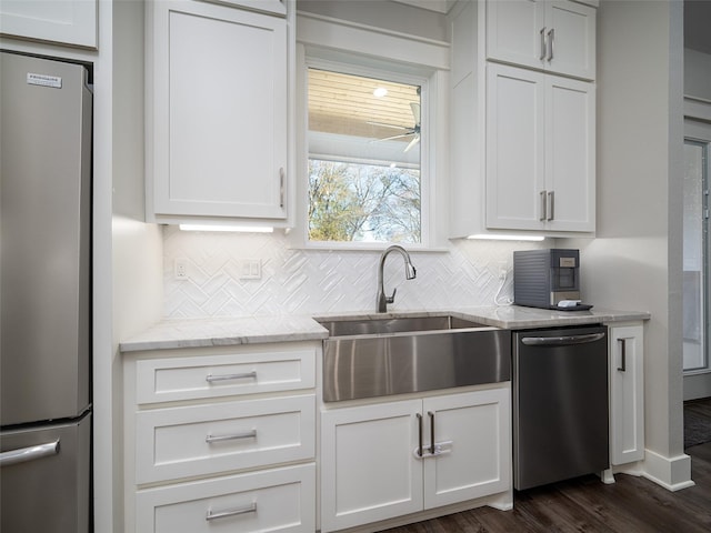 kitchen featuring sink, dark wood-type flooring, light stone counters, white cabinets, and appliances with stainless steel finishes