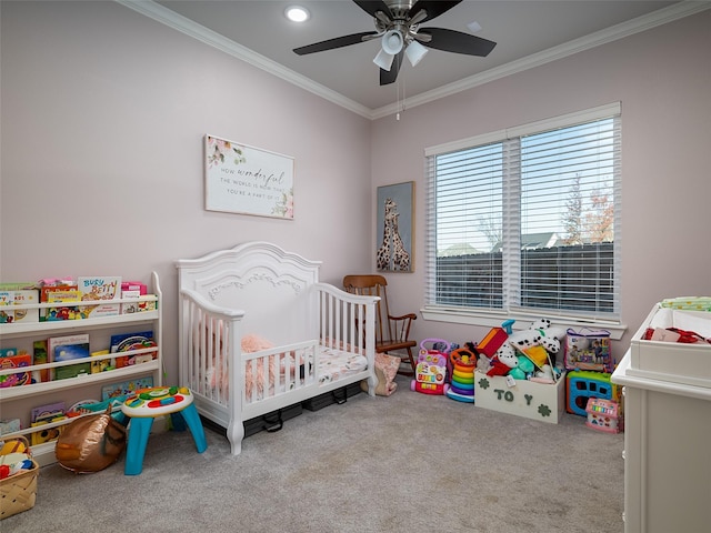 carpeted bedroom with a nursery area, ornamental molding, and ceiling fan