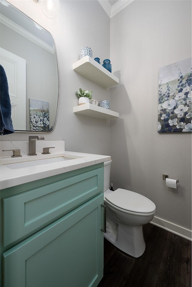 bathroom featuring toilet, vanity, wood-type flooring, and ornamental molding