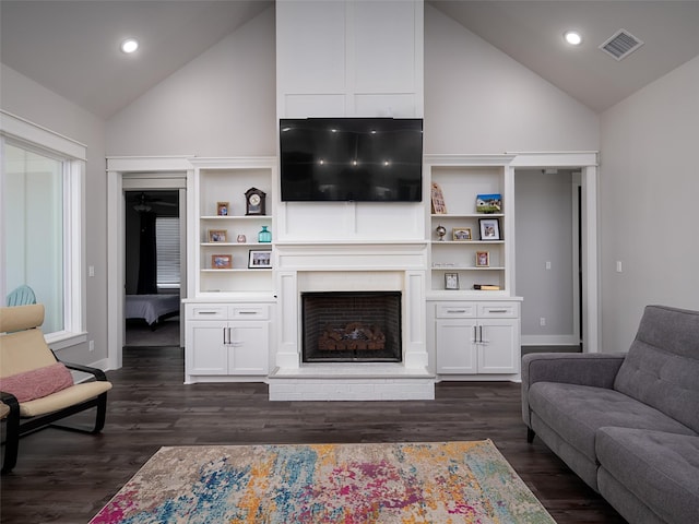 living room featuring dark wood-type flooring, vaulted ceiling, and a brick fireplace