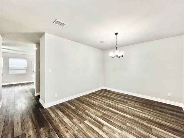 spare room with dark hardwood / wood-style flooring, a textured ceiling, and an inviting chandelier