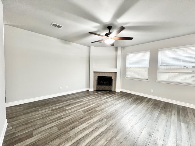 unfurnished living room with a tile fireplace, ceiling fan, and dark hardwood / wood-style floors