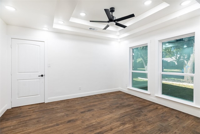 unfurnished room with a raised ceiling, ceiling fan, and dark hardwood / wood-style floors