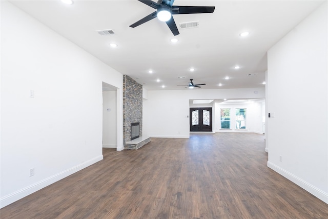 unfurnished living room featuring ceiling fan, a stone fireplace, and dark wood-type flooring