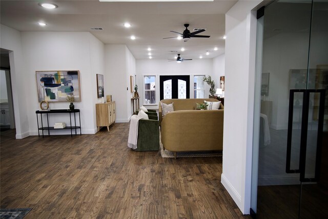 unfurnished living room with ceiling fan, a barn door, dark hardwood / wood-style flooring, and french doors