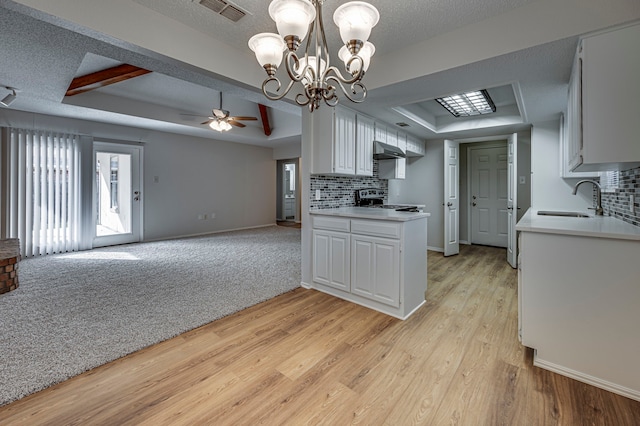 kitchen featuring ceiling fan with notable chandelier, a tray ceiling, light hardwood / wood-style flooring, white cabinets, and stainless steel electric range oven