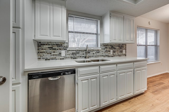 kitchen with dishwasher, white cabinets, sink, light wood-type flooring, and a textured ceiling