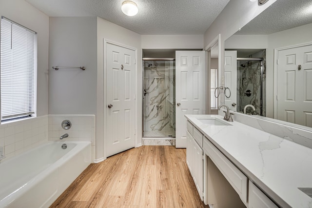 bathroom featuring separate shower and tub, vanity, a textured ceiling, and hardwood / wood-style flooring