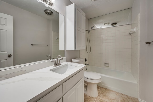 full bathroom featuring tiled shower / bath combo, tile patterned flooring, a textured ceiling, toilet, and vanity