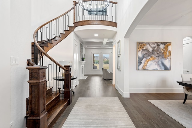 foyer entrance featuring coffered ceiling, a chandelier, ornamental molding, dark hardwood / wood-style floors, and beam ceiling