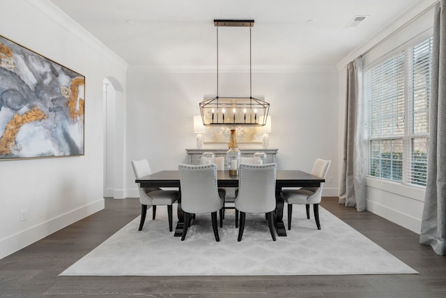 dining space with ornamental molding, dark wood-type flooring, a wealth of natural light, and a notable chandelier