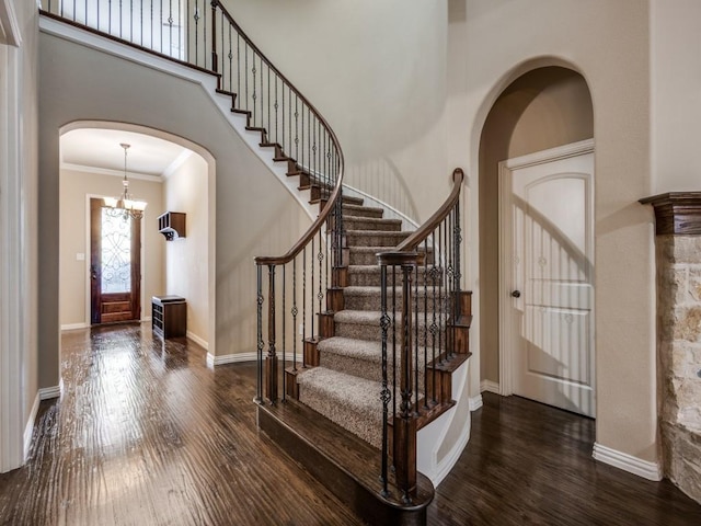 entryway featuring a high ceiling, dark hardwood / wood-style flooring, an inviting chandelier, and ornamental molding