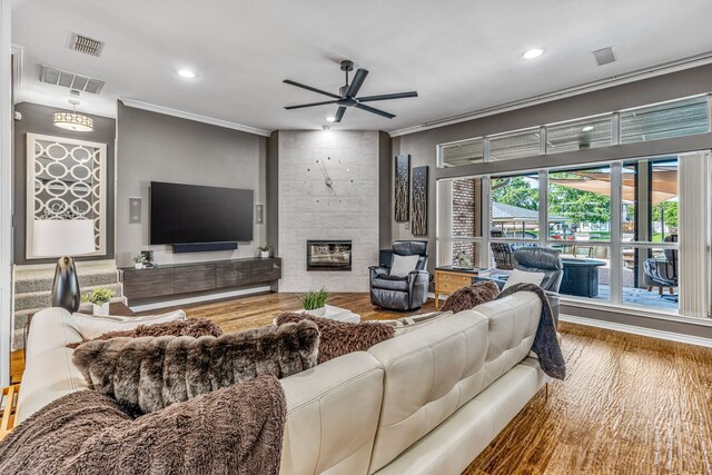 living room with a fireplace, hardwood / wood-style floors, ceiling fan, and ornamental molding