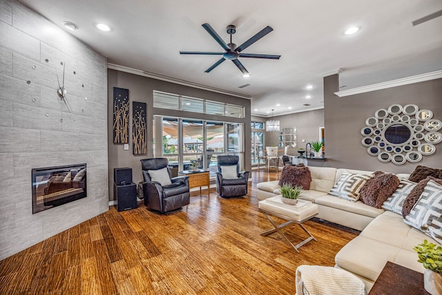 living room with hardwood / wood-style flooring, ceiling fan, ornamental molding, and a fireplace