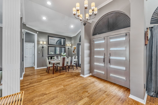 foyer featuring light wood-type flooring, crown molding, and a chandelier