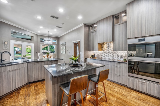 kitchen with sink, pendant lighting, a kitchen bar, a kitchen island, and light wood-type flooring