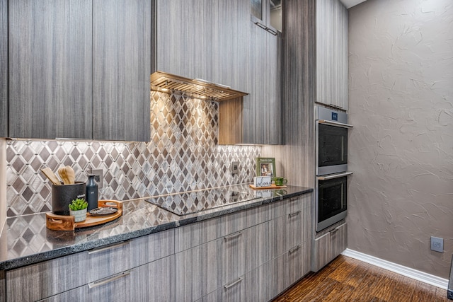 kitchen featuring black electric stovetop, backsplash, dark stone counters, and dark wood-type flooring