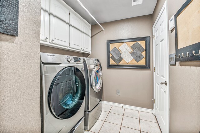 clothes washing area featuring separate washer and dryer, light tile patterned flooring, and cabinets